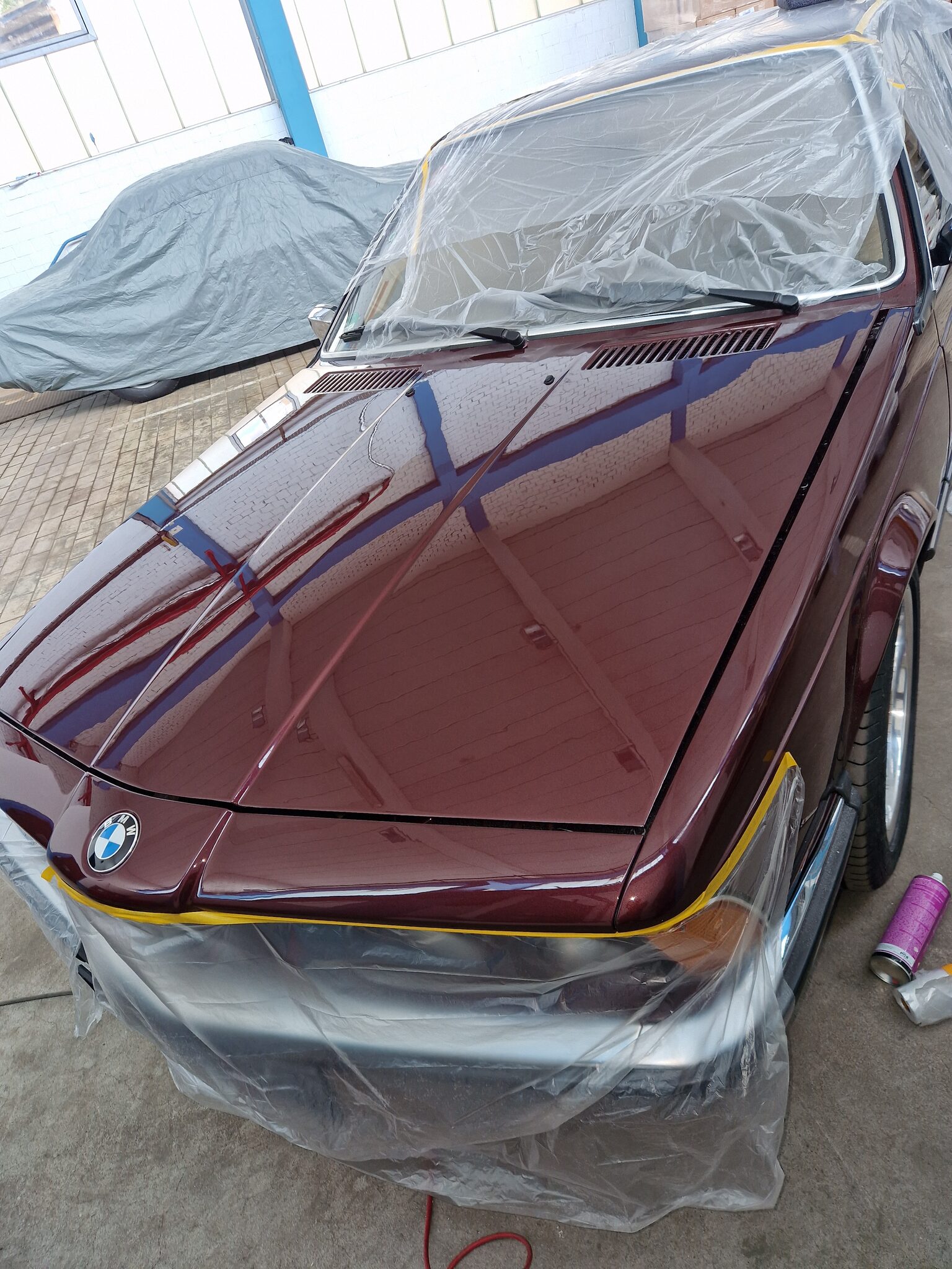 Bordeauxroter BMW 635CSi in der Werkstatt, frisch lackiert und noch abgeklebt