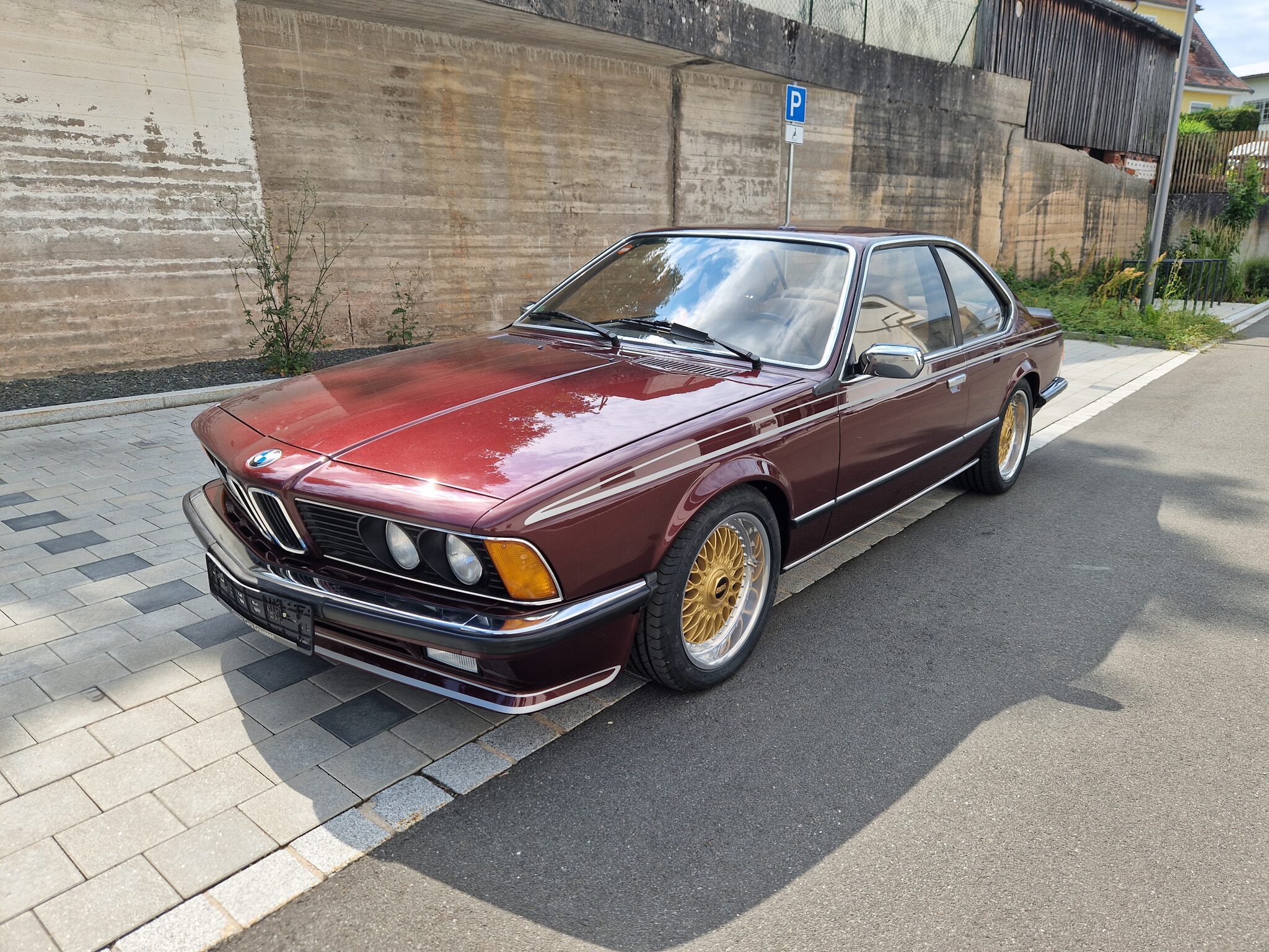 Bordeauxroter BMW 635CSi (E24) mit goldenen Kreuzspeichenfelgen