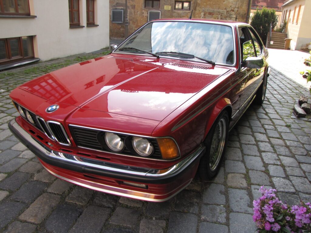 Roter BMW 635CSi (E24) auf Kopfsteinpflaster