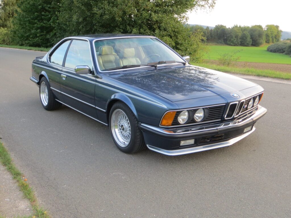 Grauer BMW E24 auf einer Landstraße