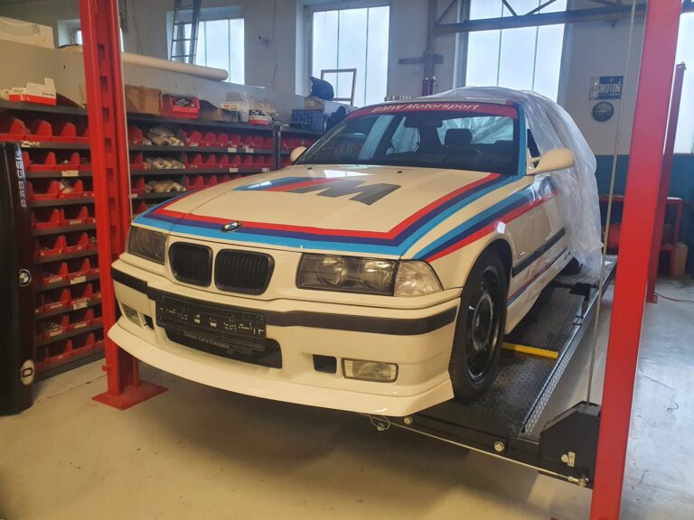 Weißer BMW E36 mit Motorsport-Streifen auf der Hebebühne